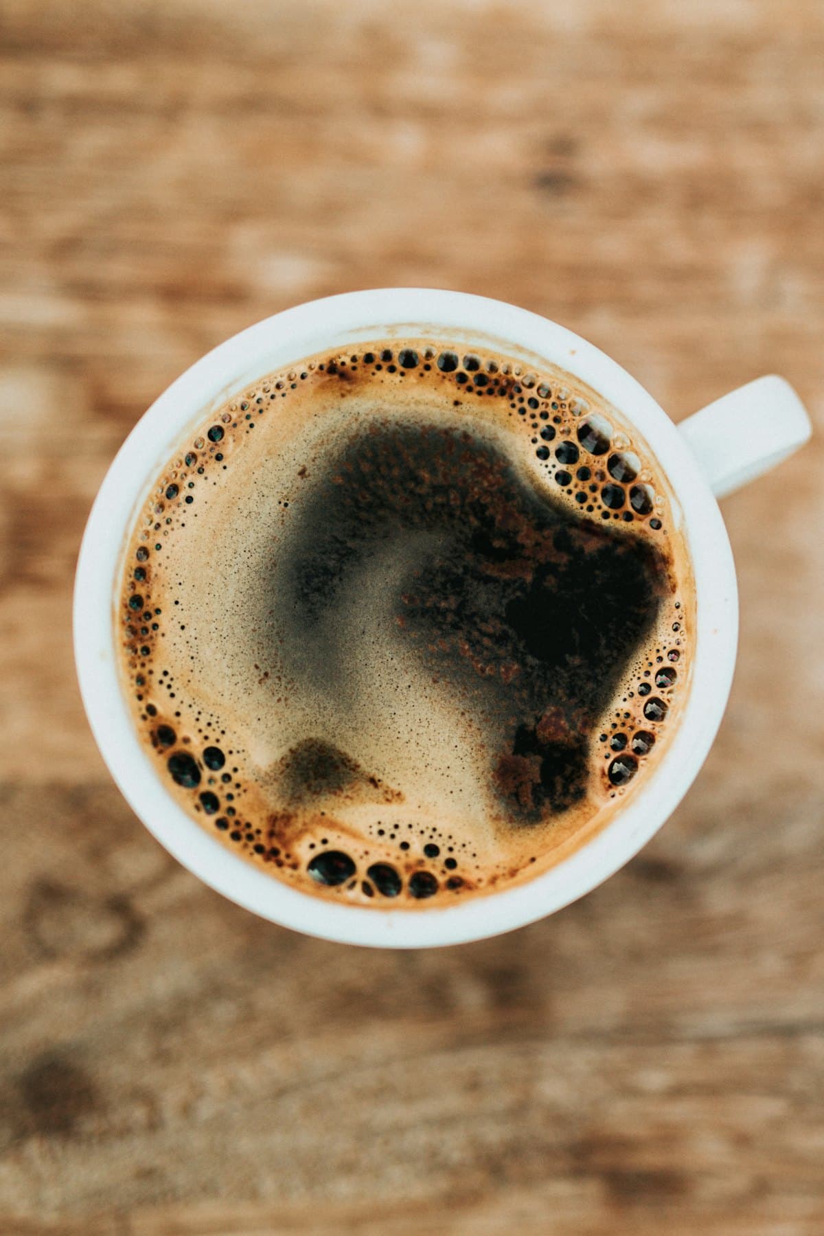 Overhead view of a black coffee with crema in a white cup
