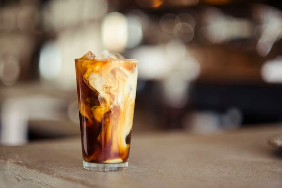 An iced coffee with swirling milk in a tall glass