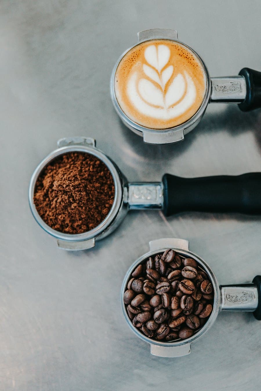 A latte with foam art next to a portafilter of ground coffee