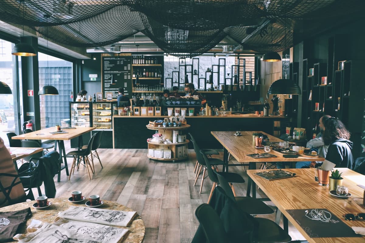 Inside the café with cane chairs, plants and the coffee bar behind